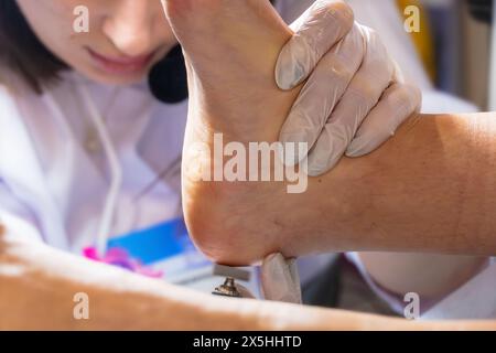 Un cosmetologo professionista fa una pedicure hardware sulla gamba di una donna nella cabina. Primo piano sul tallone delle gambe e la procedura di hardware Pedic Foto Stock