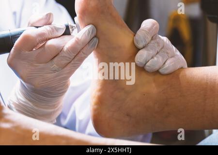 Un cosmetologo professionista fa una pedicure hardware sulla gamba di una donna nella cabina. Primo piano sul tallone delle gambe e la procedura di hardware Pedic Foto Stock