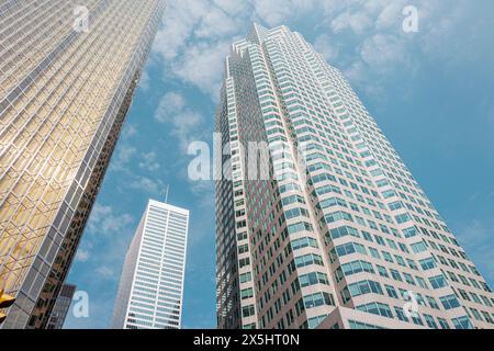 Vista dal basso del moderno ufficio dei grattacieli nel quartiere finanziario della città di Toronto, con un suggestivo cielo blu e morbide nuvole. Foto Stock