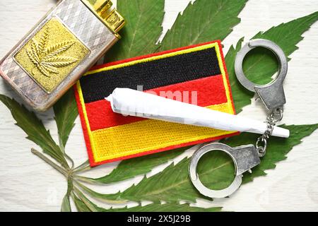 Joint und Deutschland-Fahne auf Cannabis-Blatt mit Handschellen, Cannabis-Legalisierung Foto Stock