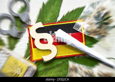 Joint, Paragrafenzeichen und Deutschland-Fahne auf Cannabis-Blatt mit Handschellen, Cannabis-Legalisierung Foto Stock