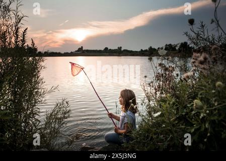 Giovane ragazza che prende le zanne nel lago al tramonto Foto Stock