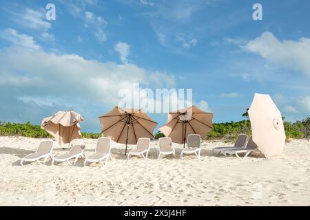 Una fila di lettini da spiaggia vuoti e ombrelloni rovesciati su una S bianca Foto Stock