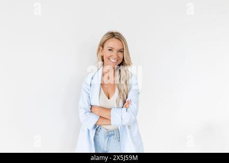 Donna sorridente con blazer blu su sfondo bianco Foto Stock