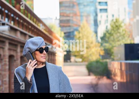 Donna allegra al telefono con paesaggio urbano sullo sfondo Foto Stock