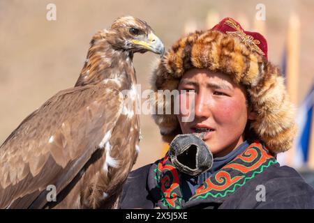 Asia, Mongolia, provincia di Bayan-Oglii. Altai Eagle Festival, giovane cacciatore di aquile kazako si prepara a coprire la sua aquila. (Solo per uso editoriale) Foto Stock