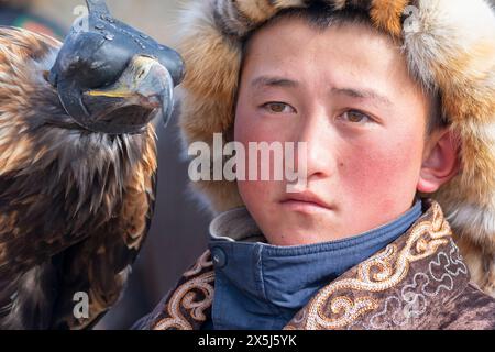 Asia, Mongolia, provincia di Bayan-Oglii. Altai Eagle Festival, ritratto di un giovane ragazzo e della sua aquila d'oro. (Solo per uso editoriale) Foto Stock