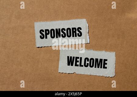 Gli sponsor accolgono le parole scritte su pezzi di carta strappati con sfondo marrone. Simbolo commerciale concettuale. Copia spazio. Foto Stock
