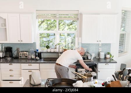 Uomo che fa piatti al lavello della cucina Foto Stock