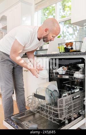 Primo piano di un uomo che carica la lavastoviglie Foto Stock