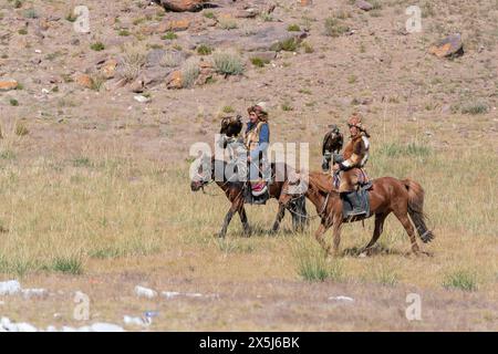 Asia, Mongolia, provincia di Bayan-Oglii. Altai Eagle Festival, due cacciatori di aquile kazaki a cavallo trasportano le loro aquile. (Solo per uso editoriale) Foto Stock
