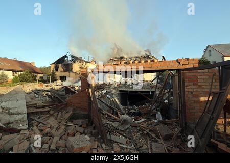 CHARKIV, UCRAINA - 10 MAGGIO 2024 - il fumo sorge sulle rovine dopo un attacco missilistico russo, Charkiv, Ucraina nord-orientale. La notte del 10 maggio, gli invasori russi attaccarono Charkiv con un missile S-300. Un bambino di 11 anni e una donna di 72 anni sono rimasti feriti a causa dell'attacco al settore privato. Tre case erano in fiamme, due di loro sono state distrutte e una è stata danneggiata. In totale, 26 edifici sono stati distrutti e più di 300 finestre sono state distrutte. Foto Stock