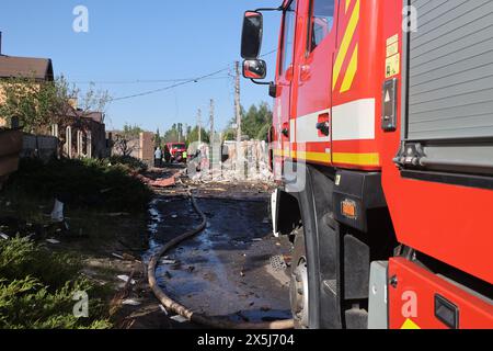 CHARKIV, UCRAINA - 10 MAGGIO 2024 - Un motore antincendio è parcheggiato nella strada colpita da un attacco missilistico russo, Charkiv, Ucraina nord-orientale. La notte del 10 maggio, gli invasori russi attaccarono Charkiv con un missile S-300. Un bambino di 11 anni e una donna di 72 anni sono rimasti feriti a causa dell'attacco al settore privato. Tre case erano in fiamme, due di loro sono state distrutte e una è stata danneggiata. In totale, 26 edifici sono stati distrutti e più di 300 finestre sono state distrutte. Foto Stock