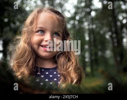 Bella bambina felice occhi blu ricci biondi sorridenti Foto Stock