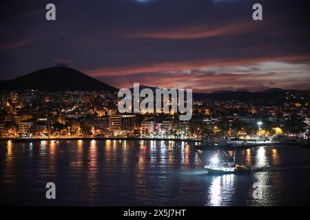 Kusadasi, Turchia. Riviera turca. Rimorchiatore sul mare vicino alla città sul lungomare con le montagne e l'alba rosa Foto Stock