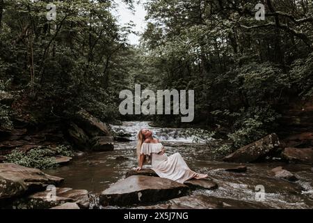 Donna incinta del terzo trimestre in piedi nel fiume Foto Stock