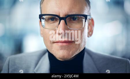 Ritratto moderno di un uomo caucasico di mezza età di successo che indossa una tuta, dolcevita e occhiali eleganti che guardano alla fotocamera. Serio, sicuro di sé, dirigente aziendale contemporaneo, imprenditore digitale Foto Stock