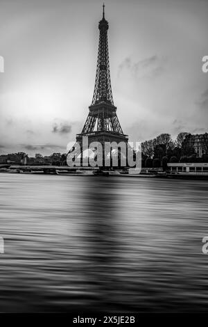 Un'accattivante immagine in bianco e nero che cattura l'iconica Torre Eiffel che si erge su un cielo nuvoloso, con il fiume Senna che scorre senza intoppi in primo piano, mostrando una bellezza senza tempo di Parigi. Francia. Immagine in bianco e nero. Foto Stock