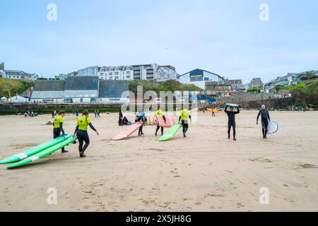 Un istruttore di surf della Escape Surf School che cammina con un gruppo di surfisti principianti sulla spiaggia di Towan a Newquay, in Cornovaglia, nel Regno Unito. Foto Stock