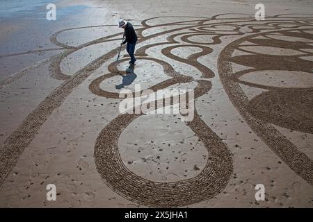 Portobello, Edimburgo, Scozia, Regno Unito. 10 maggio 2024. Neil Walker di Edimburgo ama creare disegni di Land art sulla sabbia bagnata. Quando gli è stato chiesto il titolo di questo lavoro, ha risposto pratica 69. La Land art, conosciuta anche come Earth art, Environmental art e Earthworks, è un movimento artistico che emerse negli anni '1960 e '1970, in gran parte associato alla Gran Bretagna e agli Stati Uniti, ma che include anche esempi provenienti da molti paesi. Temperatura 19 gradi centigradi con luce solare nebulizzata. Credito: Arch White/alamy notizie dal vivo. Foto Stock