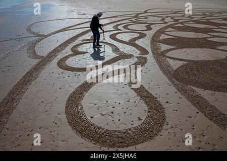 Portobello, Edimburgo, Scozia, Regno Unito. 10 maggio 2024. Neil Walker di Edimburgo ama creare disegni di Land art sulla sabbia bagnata. Quando gli è stato chiesto il titolo di questo lavoro, ha risposto pratica 69. La Land art, conosciuta anche come Earth art, Environmental art e Earthworks, è un movimento artistico che emerse negli anni '1960 e '1970, in gran parte associato alla Gran Bretagna e agli Stati Uniti, ma che include anche esempi provenienti da molti paesi. Temperatura 19 gradi centigradi con luce solare nebulizzata. Credito: Arch White/alamy notizie dal vivo. Foto Stock