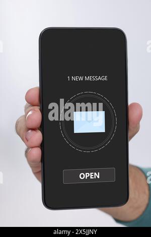 Uomo che mostra un telefono cellulare con la notifica di un nuovo messaggio sullo schermo su sfondo bianco, primo piano Foto Stock