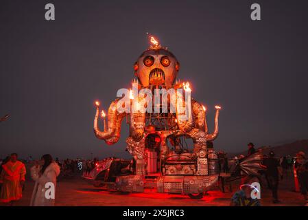 Scena del festival con grande installazione artistica di polpo nel deserto al crepuscolo Foto Stock