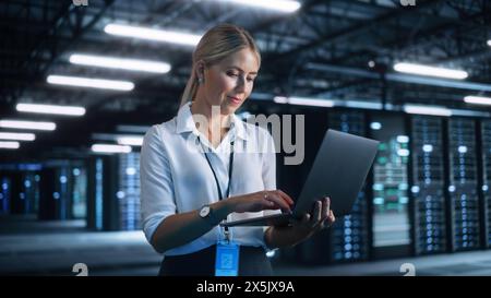 Donna d'affari che lavora con un computer portatile nel suo ufficio. Skilful CEO femminile gestisce Business Company durante la serata. Servizio cloud, trasferimento server e analisi Foto Stock