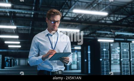 Il tecnico IT lavora su un tablet nel Big Data Center di notte. Esegue la diagnostica e la manutenzione, imposta il sistema. Servizio cloud, trasferimento server e analisi Foto Stock