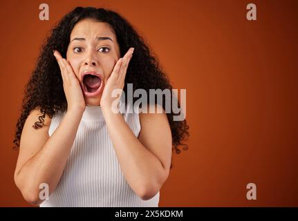Donna, ritratto e scioccata in studio per notizie tristi, annunci e urla di paura. Modello brasiliano, wtf e sorpreso su sfondo isolato Foto Stock