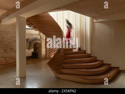 Scala scultorea in legno ricurvo con figura ascendente. ACME Offices, Londra, Regno Unito. Architetto: ACME, 2024. Foto Stock