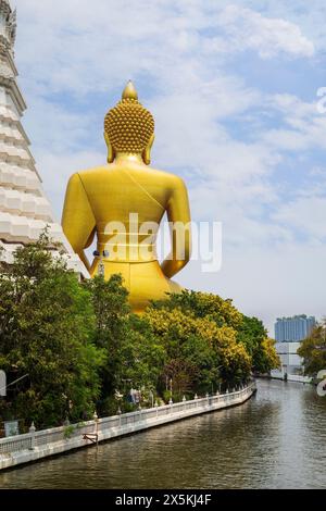 Sul retro della grande, alta e dorata statua del Buddha presso il Tempio di Wat Paknam (Pak Nam) Phasi Charoen presso un canale (khlong) a Bangkok, Thailandia, di giorno. Foto Stock