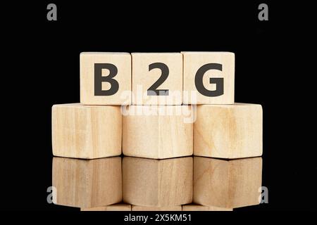 B2G è l'abbreviazione di Business to Government, il testo scritto su cubi di legno su sfondo nero Foto Stock