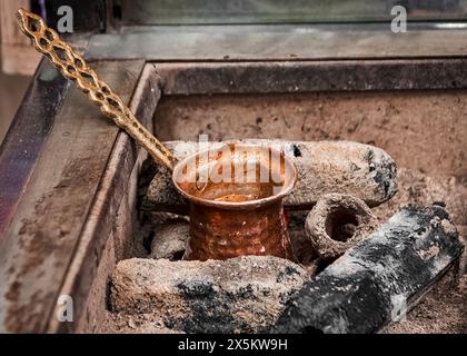 Tipico contenitore in bronzo posto su carboni caldi per la preparazione del caffè turco Foto Stock