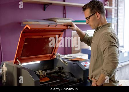 l'artigiano creativo e attivo professionista crea un motivo in rilievo su una superficie in pelle su cintura, portafoglio e borsa. immagine con vista laterale ravvicinata Foto Stock