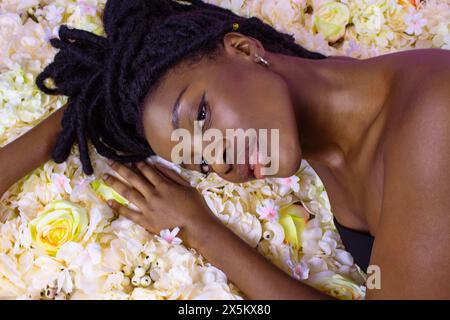 Ritratto in studio di una giovane donna sdraiata sui fiori Foto Stock