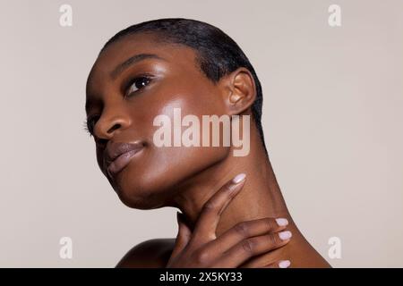 Giovane donna di toccare il collo Foto Stock