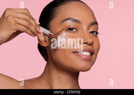 Giovane donna che usa il rullo di giada Foto Stock