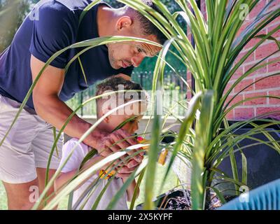 Padre con figlio annaffiatoio nel cortile posteriore Foto Stock