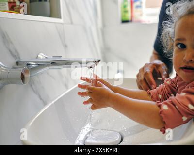 Primo piano del padre che aiuta la figlia a lavarsi le mani Foto Stock