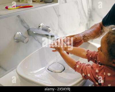 Primo piano del padre che aiuta la figlia a lavarsi le mani Foto Stock