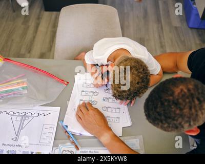 Padre che assiste il figlio a fare i compiti a casa Foto Stock