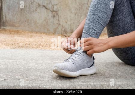 Primo piano di una donna che lega i lacci a scarpe sportive prima dell'allenamento Foto Stock