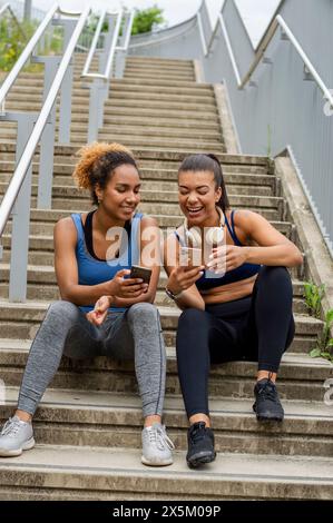 Amiche sportive che usano i telefoni Foto Stock