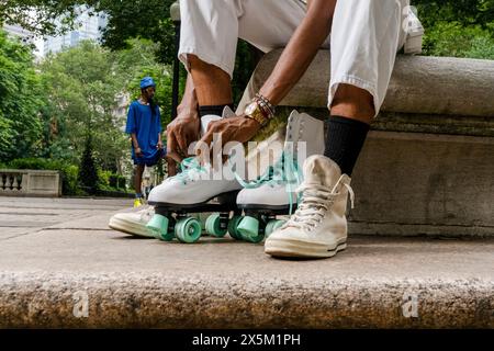 USA, gambe di donna che si mette su pattini a rotelle nel parco Foto Stock