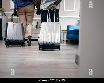 Regno Unito, vista posteriore della coppia matura con valigie che entrano nella hall dell'hotel Foto Stock