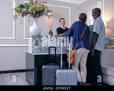 Regno Unito, coppia matura con valigie alla reception dell'hotel Foto Stock