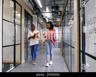 Due donne che camminano nel corridoio dell'ufficio Foto Stock