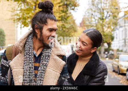 Una coppia che cammina lungo la strada in autunno Foto Stock