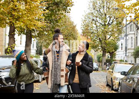 Gruppo di amici che camminano per strada in autunno Foto Stock
